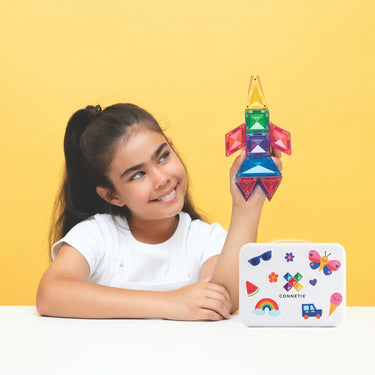 Girl playing with Connetix Tiles, holding a colorful rocket from the Travel Mini Pack 32pcs.